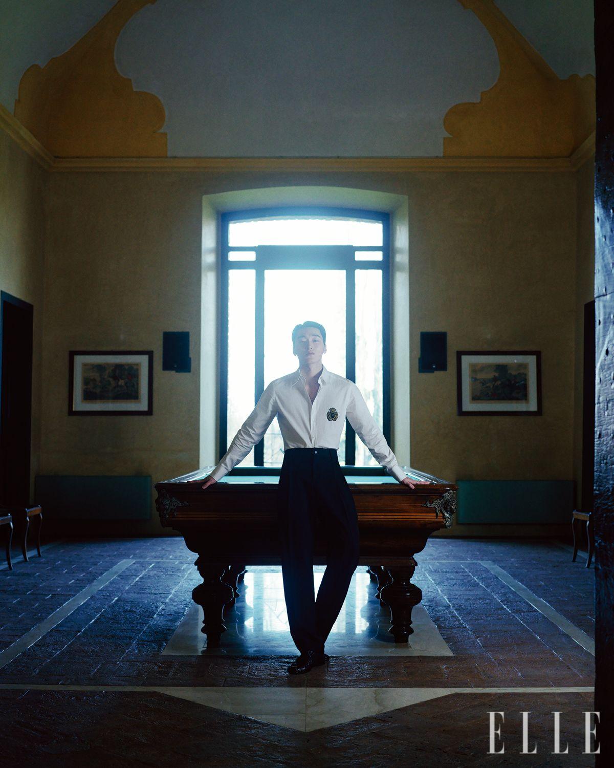 산이 입은 휘장 패치로 장식한 셔츠와 팬츠, 더비 슈즈는 모두 Dolce & Gabbana.