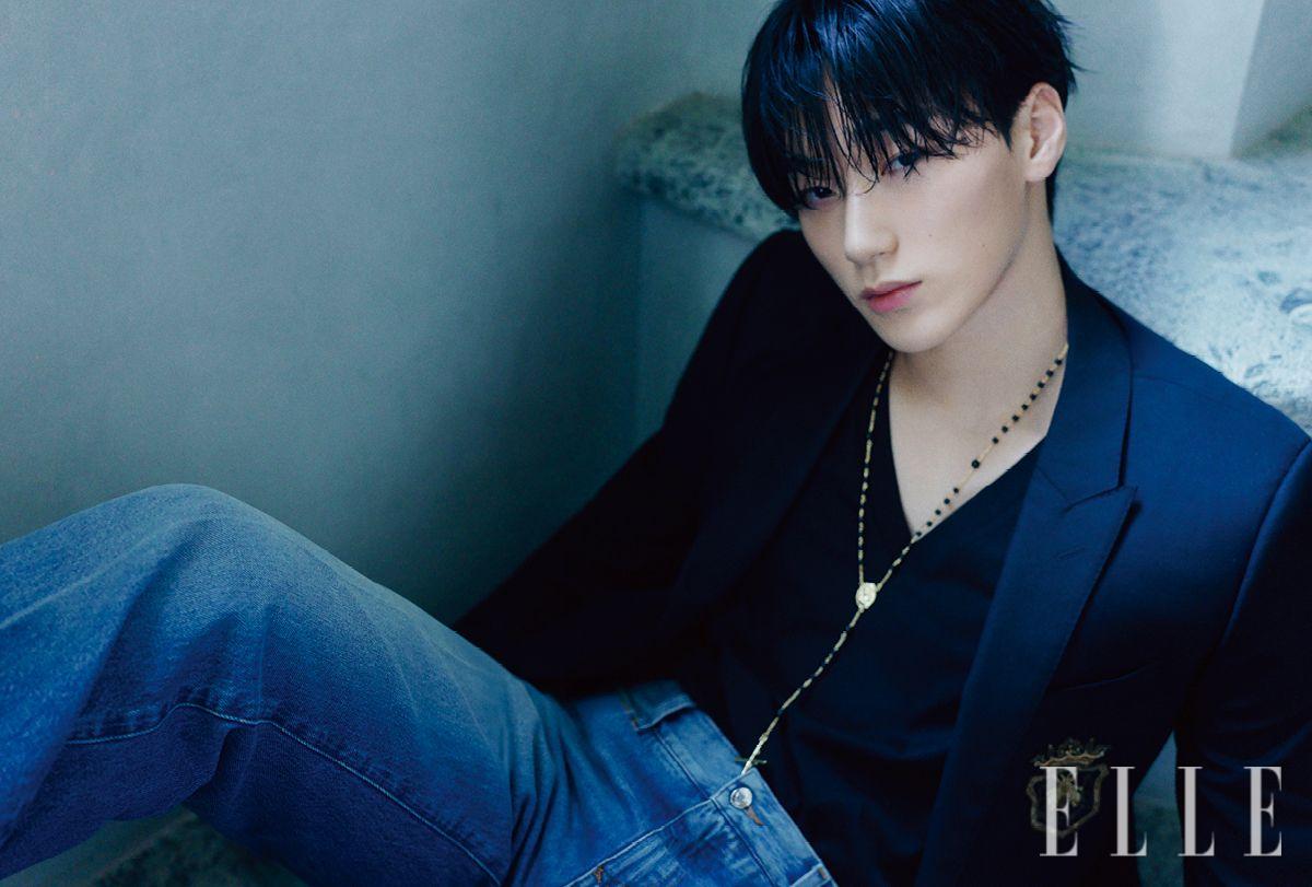 산이 입은 패치 장식의 블레이저와 티셔츠, 데님 팬츠, 십자가 펜던트 네크리스는 모두 Dolce & Gabbana.