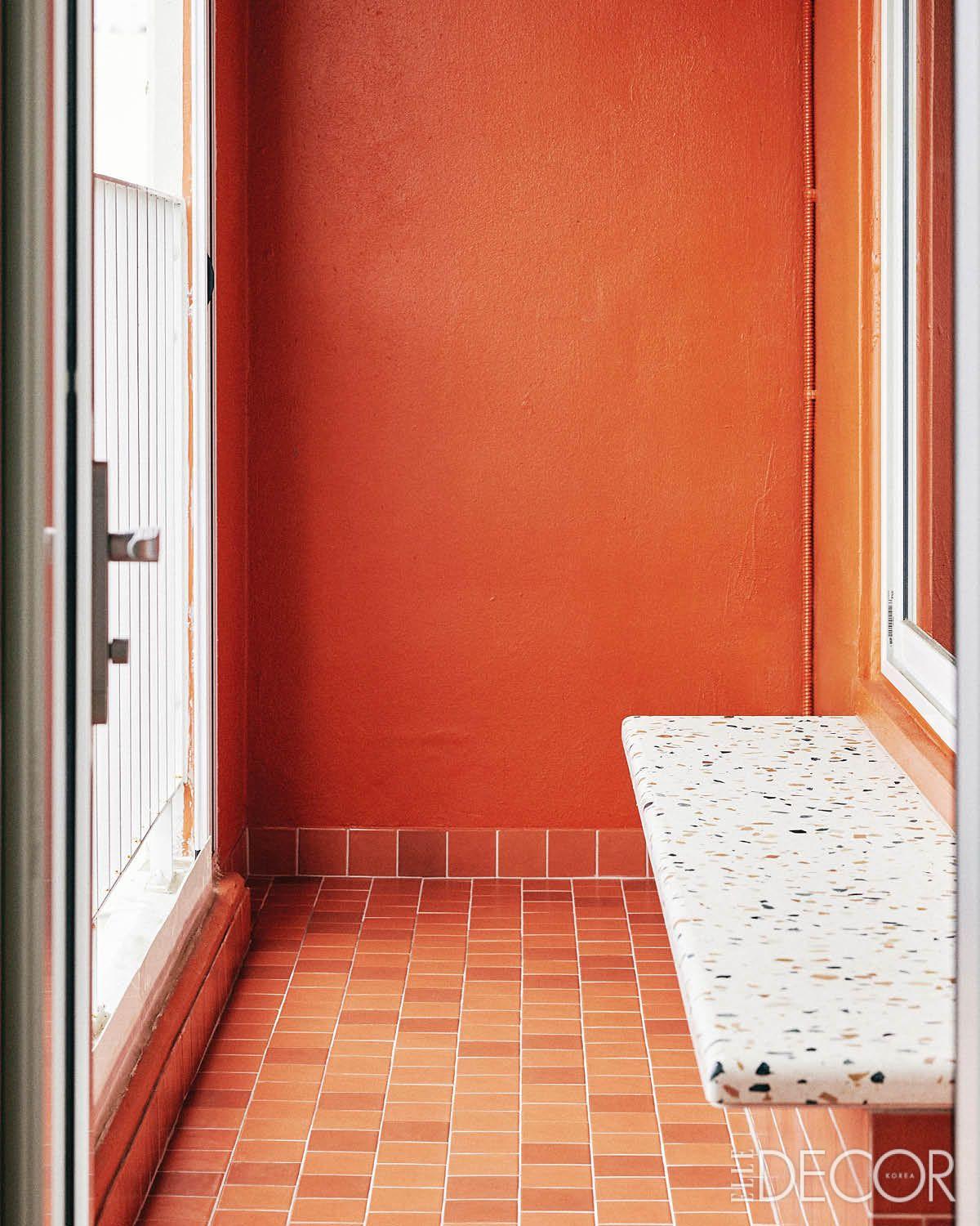 붉은색 도장과 타일, 주방 카운터석과 동일한 소재로 만든 벤치가 있는 발코니.