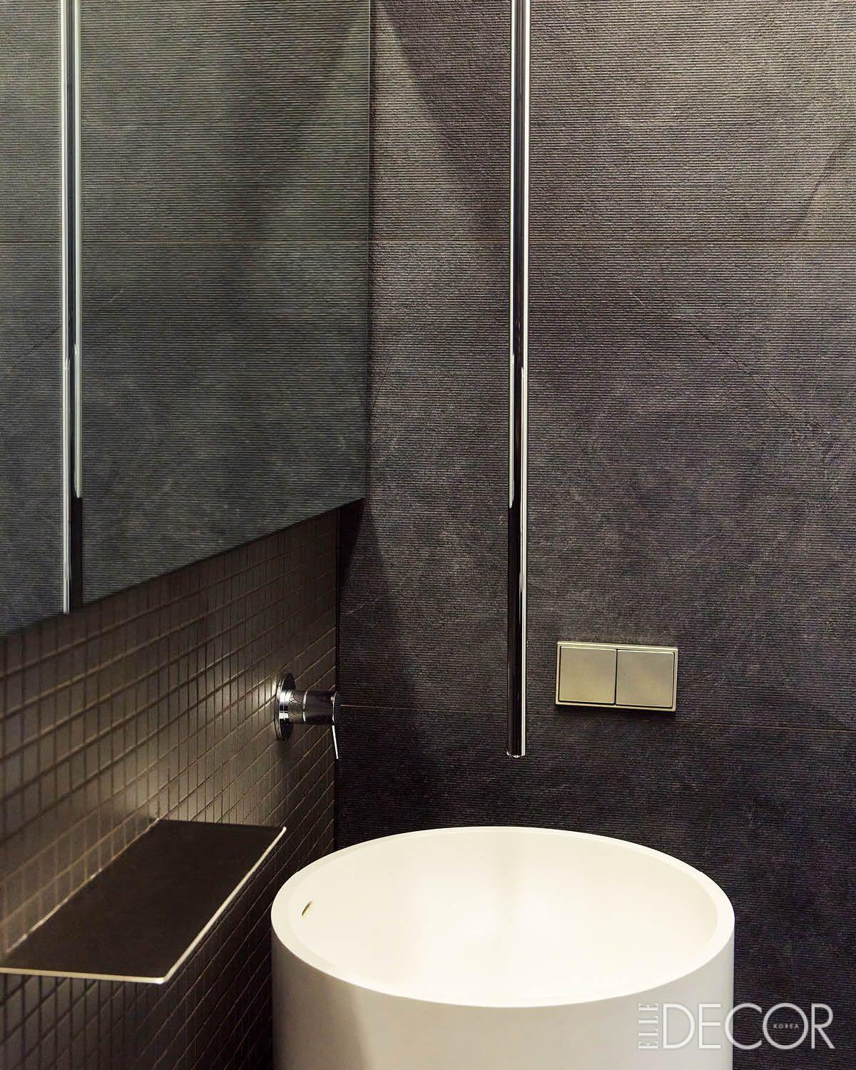 블랙 컬러로 마감한 게스트 욕실은 전체 공간에 강렬한 대비를 주며, 천장형 매립 수전이 간결한 조형미를 더한다. 외관 일부에는 나무 패널로 포인트를 줘 주변 정원과 조화를 이루도록 했다.