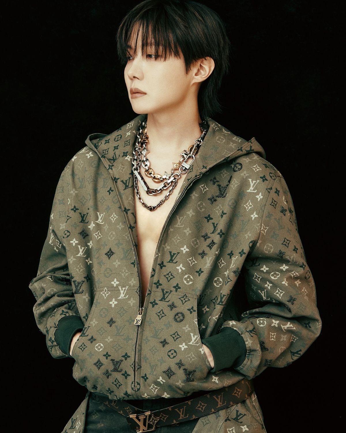 제이홉이 입은 모노그램 엠벨리시드 후디드 블루종과 데님 팬츠, 허리에 두른 워크웨어 오버 셔츠, 벨트, 목걸이로 레이어드한 체인 벨트와 백 참은 모두 Louis Vuitton.