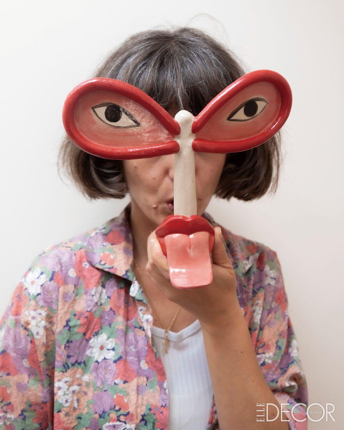 혀 모양의 오브제이자 악기인 ‘자궁의 휘파람(Silbas Uterinas)’을 들고 있는 라이아 아르케로스 클라라문트. 여성의 목소리를 지워온 역사에 대한 은유적 저항이 스며 있다.