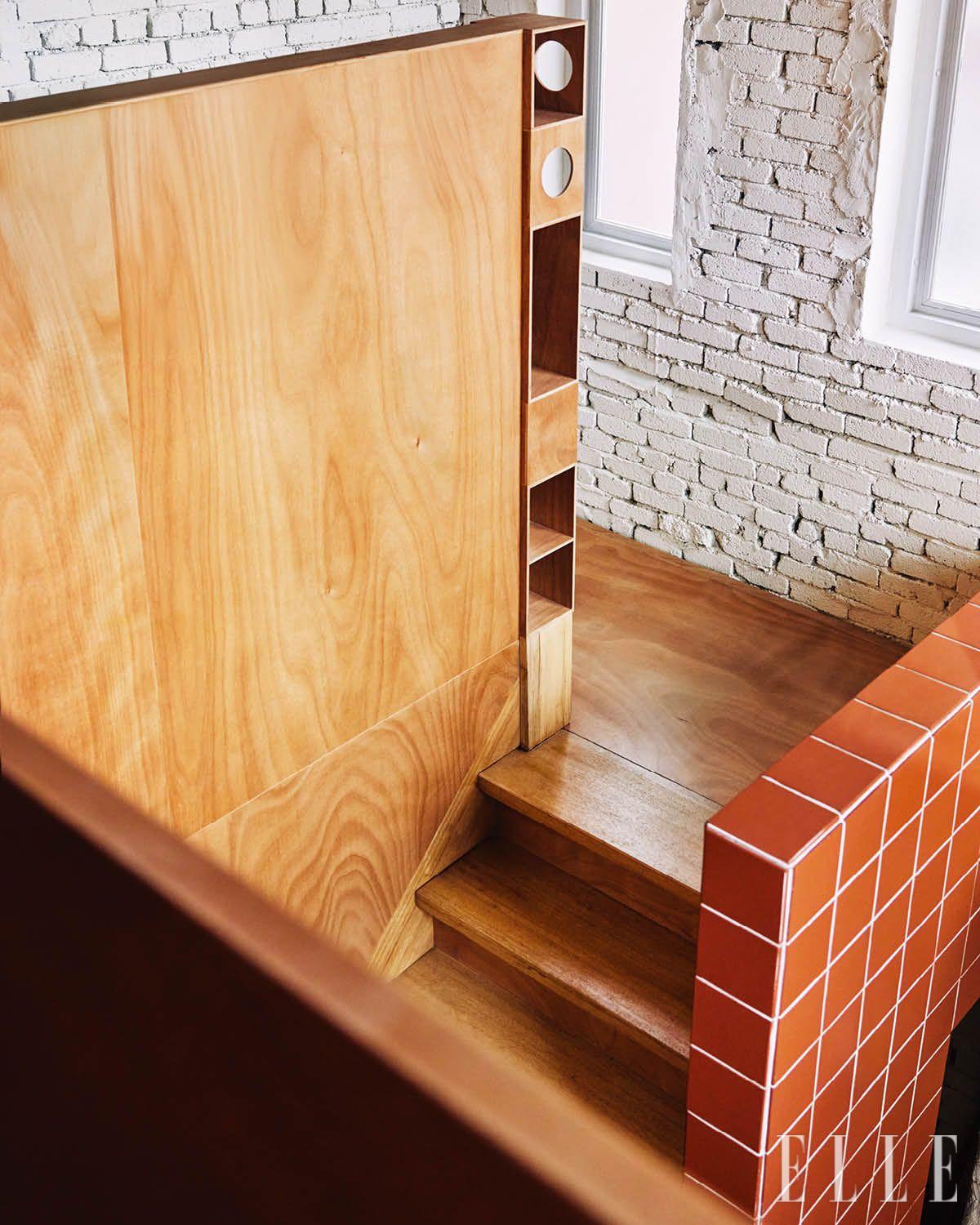 붉은색 타일과 목재 벽이 마주보는 계단, 동그란 구멍을 뚫어 만든 세라믹 조각 진열대. 