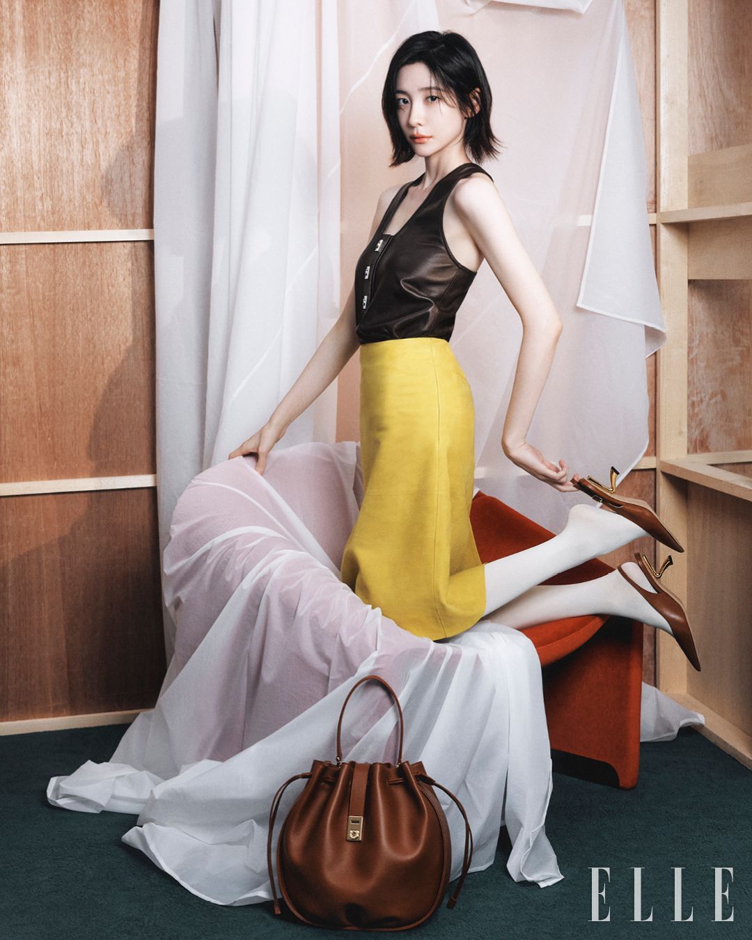 드로스트링 여밈이 풍성한 주름을 완성하는 허그 버클 버킷 백, 아이코닉한 간치니 장식의 카프스킨 슬리브리스 톱, 카프스킨 미디스커트, F힐 슬링백 슈즈는 Ferragamo.