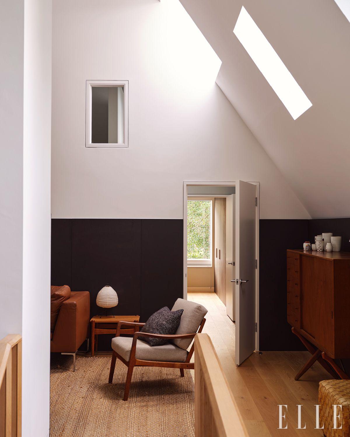 사이드 테이블 위에는 이사무 노구치(Isamu Noguchi)의 아카리 테이블 램프가 놓여 있다. 천장을 낮추고, 우드 울 흡음 패널을 매달아 음향을 부드럽게 다듬은 거실.