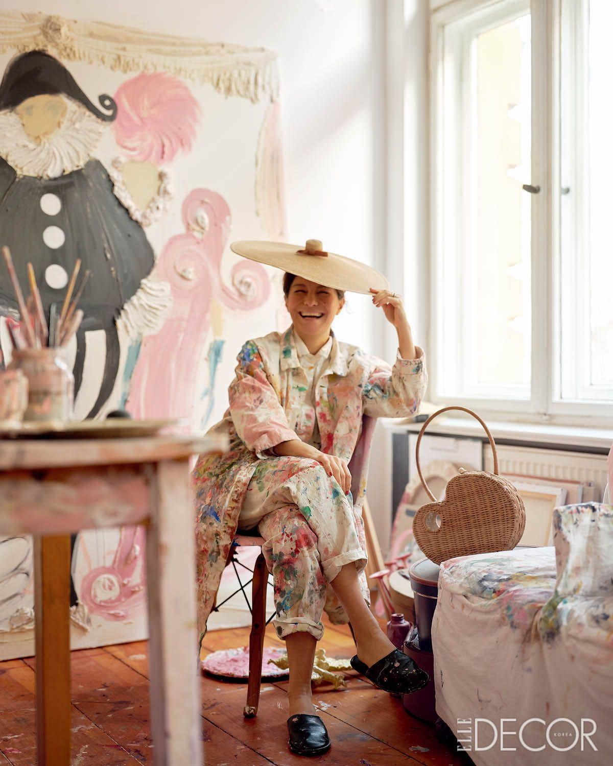 작업실 테이블 뒤, 대형 회화 앞에 자리한 메리엄. 옷 여기저기에 묻은 물감 자국이 그림을 향한 메리엄의 열정을 보여준다. 