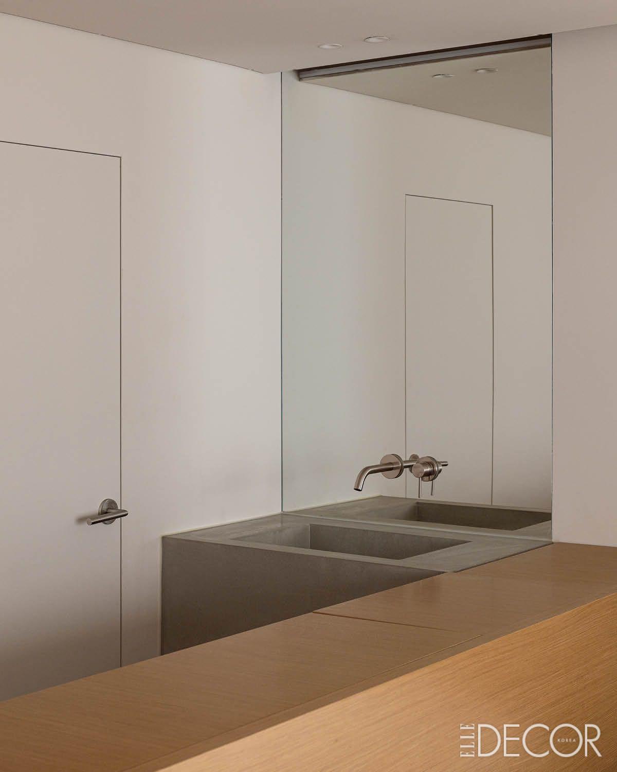 묵직한 석재 세면대와 거울을 통해 확장되는 공간을 대비시킨 침실의 세안 존. 