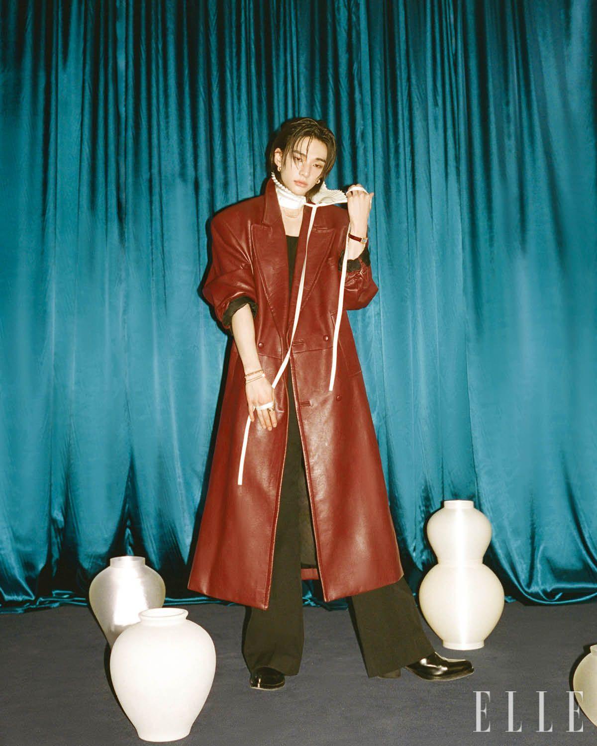 핑크골드에 핑크 칼세도니를 세팅한 클래쉬 드 까르띠에 이어링과 네크리스, 다크 브라운 앨리게이터 레더 스트랩의 스몰 탱크 아메리칸 워치, 오른손에 착용한 화이트· 핑크· 옐로골드의 트리니티 링과 핑크골드 클래쉬 드 까르띠에 스몰 & 미디엄 브레이슬릿은 모두 Cartier. 레더 롱 코트는 Bonbom. 이너 웨어 톱과 팬츠, 플리츠 디테일의 타이, 부츠는 모두 스타일리스트 소장품. 서로 다른 크기를 쌓아 올린 달항아리와 왼쪽 뒤편의 달항아리는 모두 Seasoning.objet.