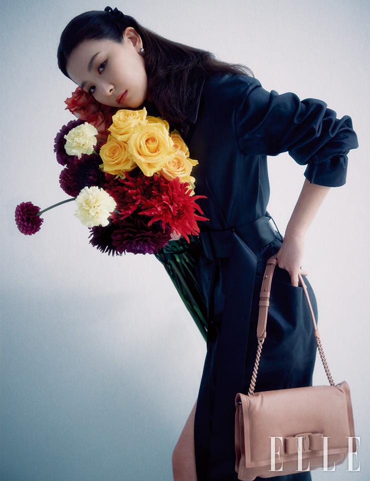 블랙 가죽 트렌치코트와 로맨틱한 페일 핑크 ‘비바 보우’ 체인 백, 진주 이어링은 모두 Salvatore Ferragamo.