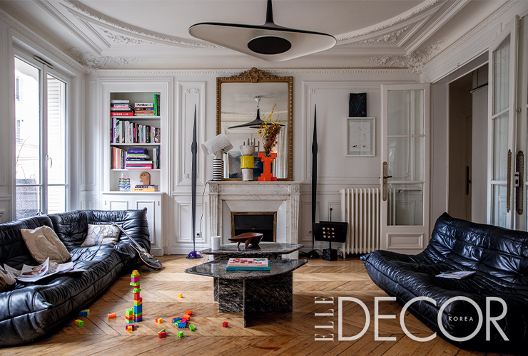 베누아와 나탈리의 거실 전경. 소파는 블랙 가죽 버전의 토고(Togo), 천장 램프는 루체플랜(Luceplan)의 솔레이 누아르(Soleil Noir).