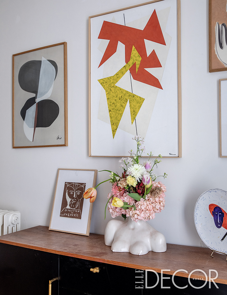 꽃병은 아니사 케르미슈(Anissa Kermiche), 벽 중앙에 걸린 매그(Maeght) 판화 에디션은 벨기에 아티스트 Vacl의 작품.