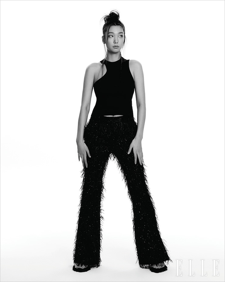 블랙 슬리브리스 톱은 Axel Arigato. 깃털 장식의 팬츠는 YCH. 페이크 퍼 뮬은 Gucci.